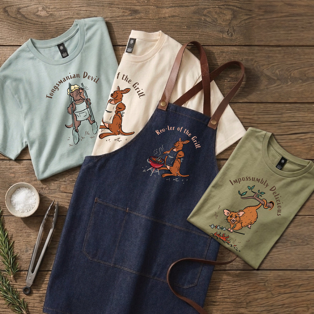 Wooby Father’s Day T-shirts and denim BBQ apron featuring hand-drawn Australian animals cooking on a wooden table