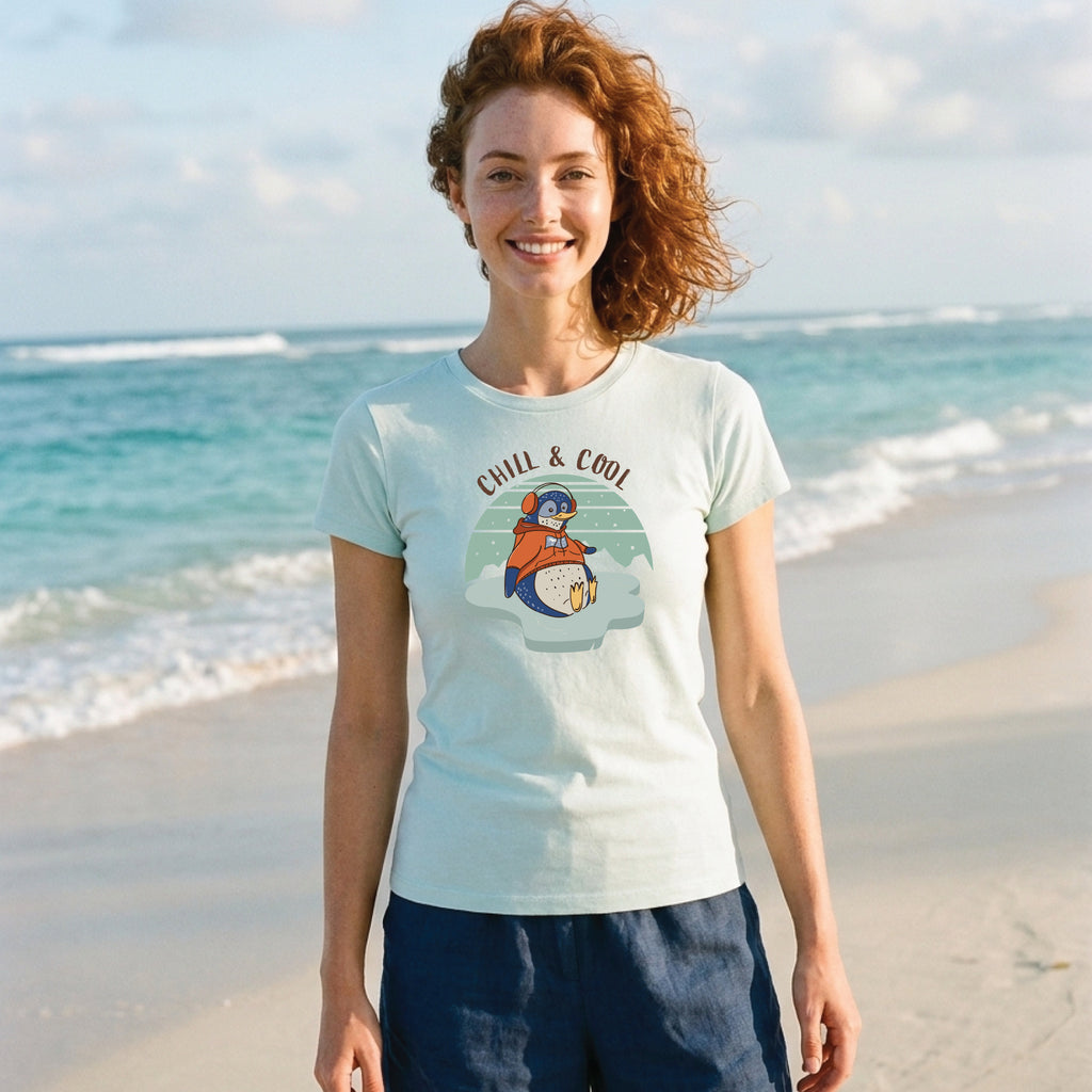 Woman wearing a Seafoam Women's Penguin T-Shirt featuring a hand-drawn penguin illustration and "Chill & Cool" slogan, enjoying a relaxed outdoor lifestyle setting.