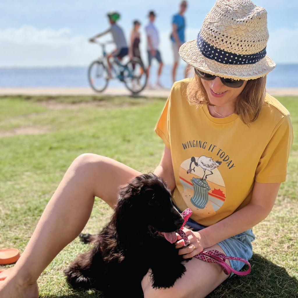Woman wearing a Funny Ibis T-Shirt featuring a hand-drawn Australian ibis design and “Winging It Today” slogan, styled in a casual outdoor lifestyle setting.