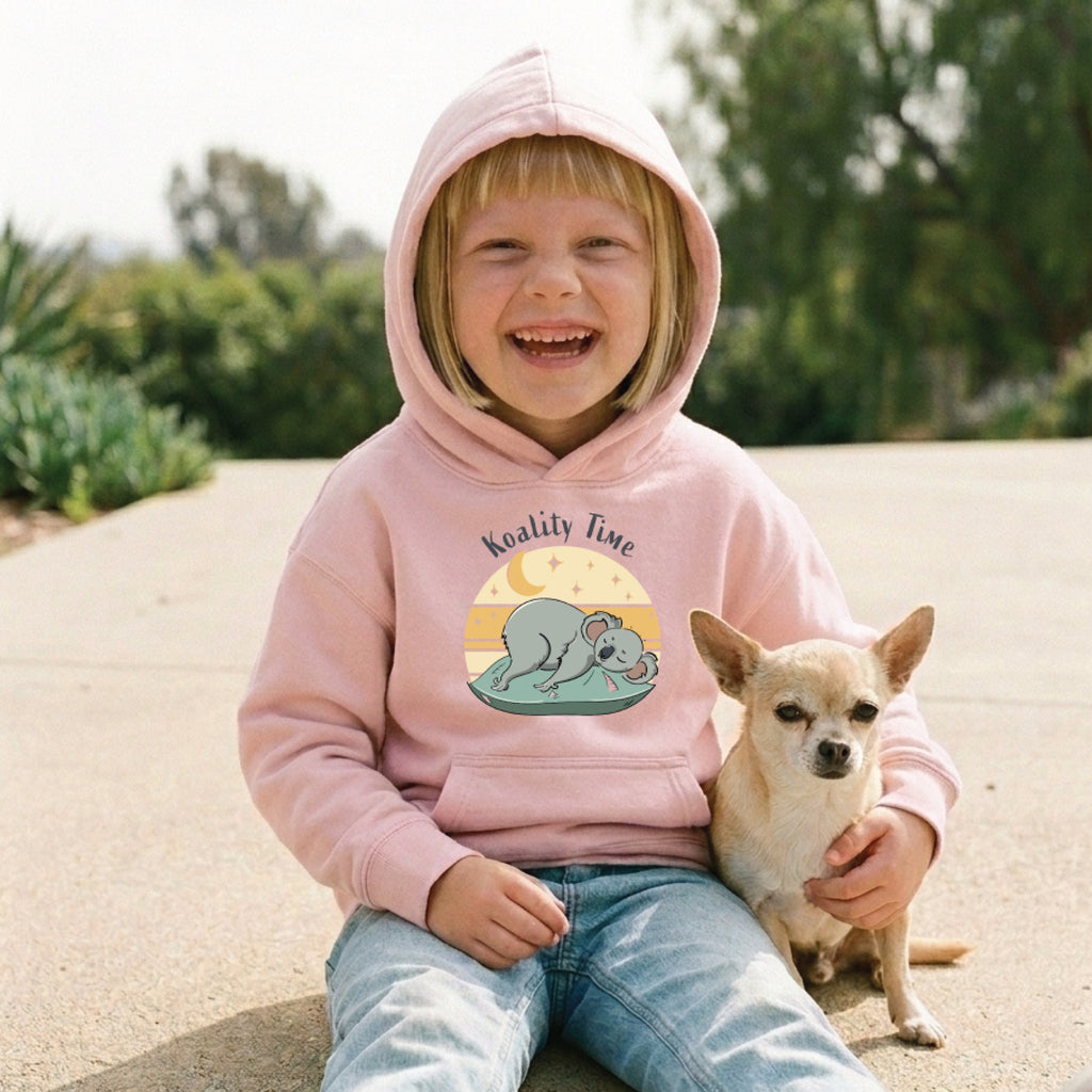 Child wearing a Kids' Koala Hoodie featuring a hand-drawn koala illustration and "Koality Time" slogan, enjoying a fun and relaxed outdoor lifestyle setting.