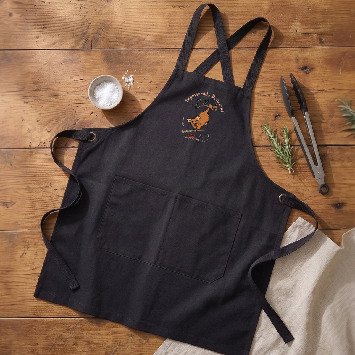 Possum BBQ apron featuring a hand-drawn possum cooking over an open fire with Impossumbly Delicious slogan